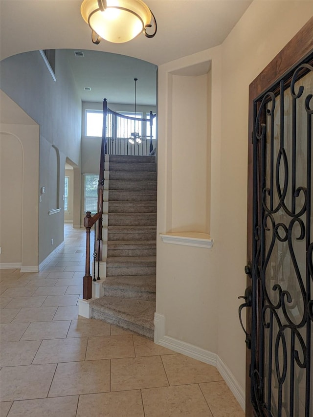 stairs featuring arched walkways, visible vents, baseboards, and tile patterned floors