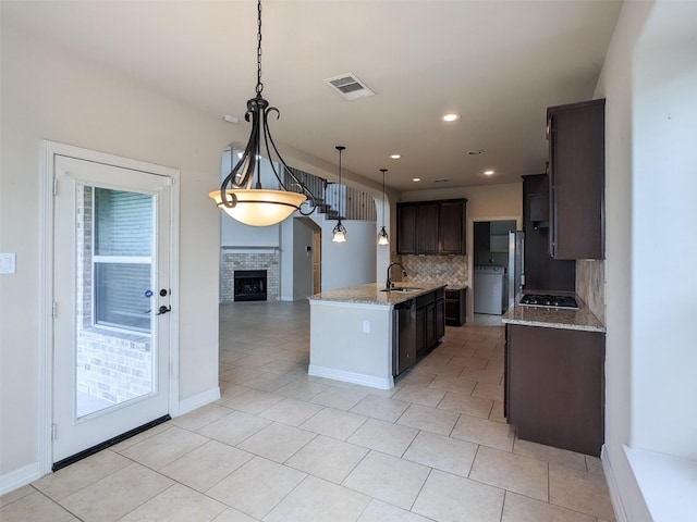 kitchen featuring a fireplace, decorative light fixtures, tasteful backsplash, sink, and dark brown cabinetry