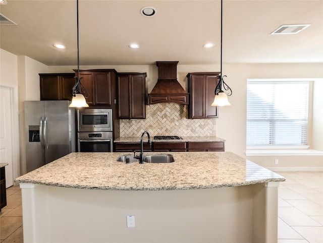 kitchen with appliances with stainless steel finishes, a kitchen island with sink, a sink, and custom exhaust hood