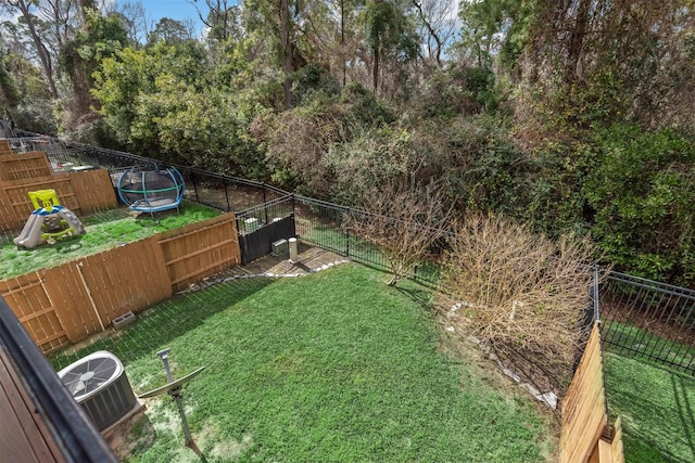 view of yard featuring a trampoline, central AC unit, and a playground