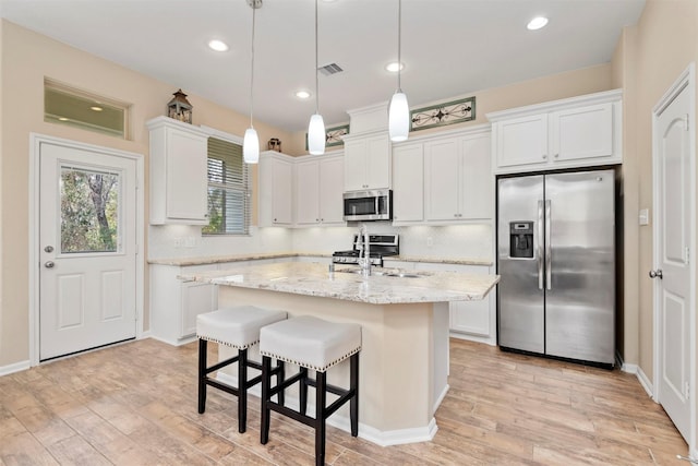 kitchen featuring white cabinetry, appliances with stainless steel finishes, decorative light fixtures, and sink