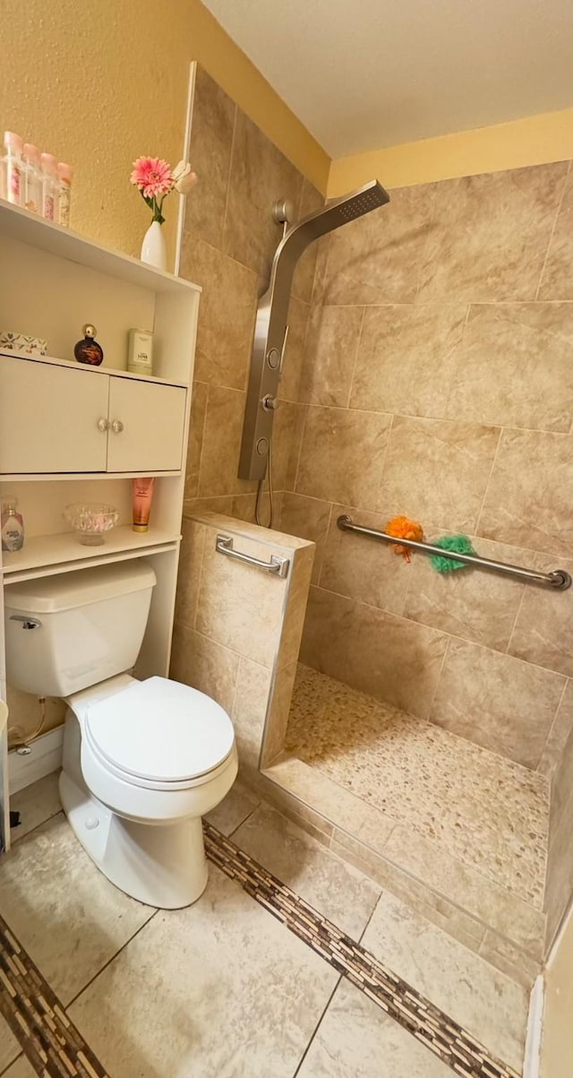 bathroom with tile patterned flooring, tiled shower, and toilet