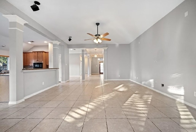 unfurnished living room featuring light tile patterned floors, vaulted ceiling, ceiling fan, and ornate columns