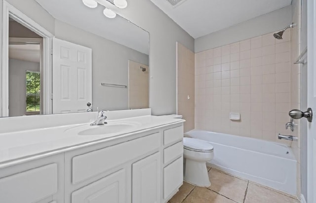 full bathroom featuring tile patterned flooring, vanity, tiled shower / bath, and toilet