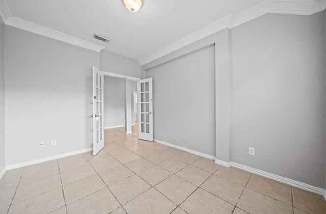 unfurnished room featuring crown molding, light tile patterned floors, and french doors