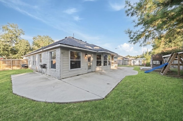 back of house featuring a yard, a patio area, and a playground