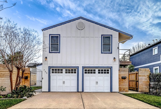 view of front of home with concrete driveway, board and batten siding, fence, and a gate