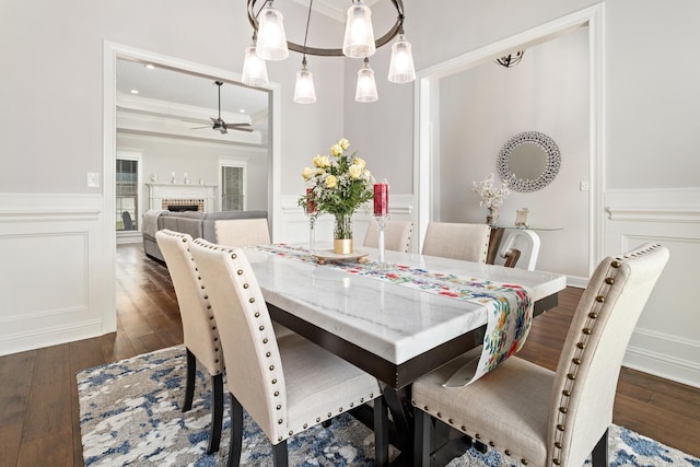 dining space featuring a brick fireplace, ornamental molding, dark hardwood / wood-style floors, and ceiling fan