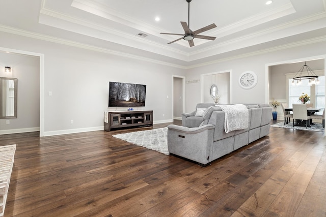 living room with crown molding, dark wood-type flooring, ceiling fan, and a tray ceiling