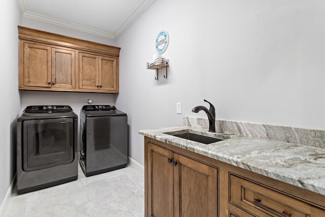 clothes washing area with sink, ornamental molding, cabinets, and washer and dryer