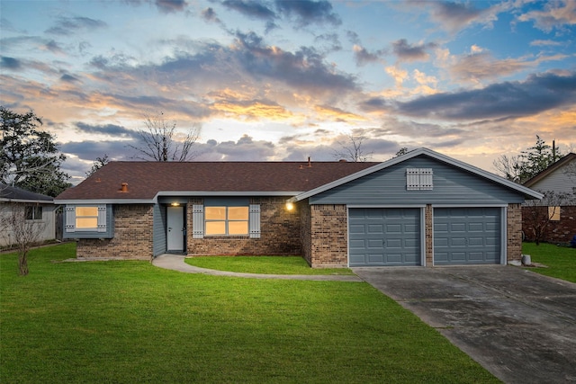 ranch-style house with a garage, a yard, brick siding, and concrete driveway