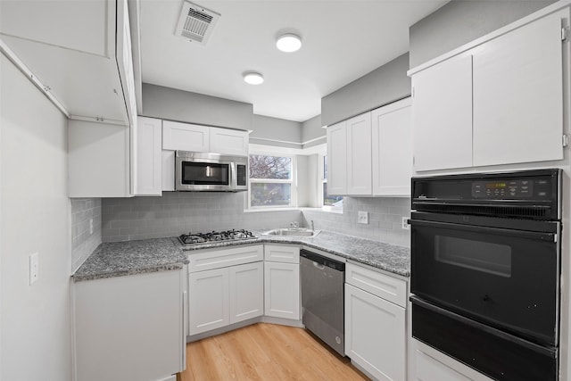 kitchen with appliances with stainless steel finishes, white cabinets, visible vents, and a sink