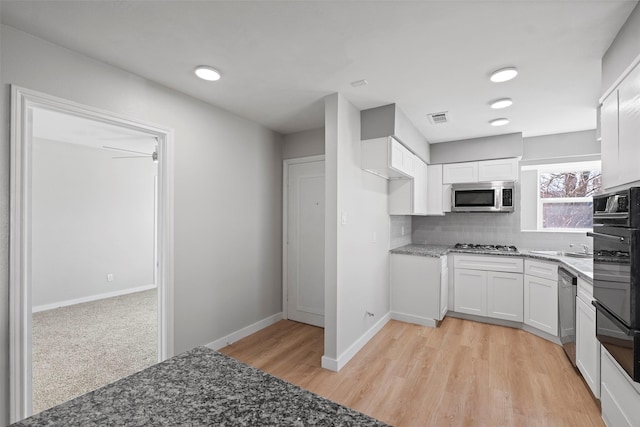 kitchen featuring visible vents, decorative backsplash, appliances with stainless steel finishes, white cabinets, and dark stone countertops