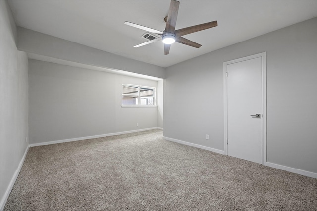 carpeted spare room with visible vents, ceiling fan, and baseboards