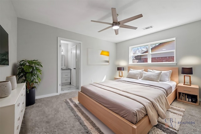 bedroom featuring light colored carpet, visible vents, ensuite bathroom, a ceiling fan, and baseboards