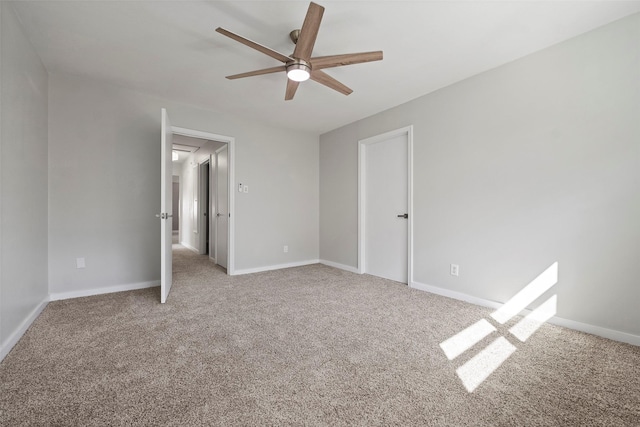 unfurnished bedroom featuring carpet, attic access, baseboards, and a ceiling fan