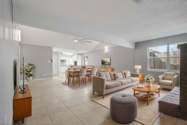 living room featuring light tile patterned floors, baseboards, ceiling fan, vaulted ceiling, and a textured ceiling