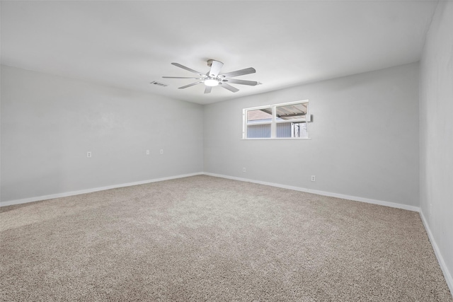 carpeted spare room with a ceiling fan, visible vents, and baseboards