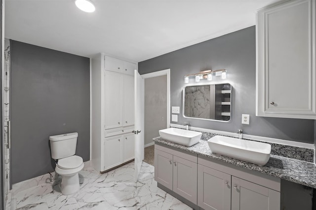 bathroom featuring marble finish floor, a sink, toilet, and double vanity