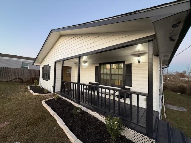 view of side of home with a porch and a yard