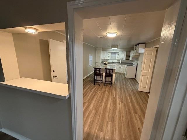 kitchen with white cabinetry, a kitchen breakfast bar, kitchen peninsula, and light wood-type flooring