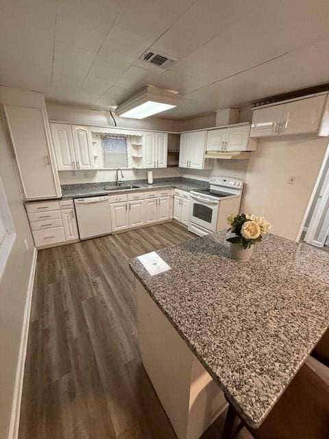 kitchen featuring white cabinetry, a kitchen bar, white appliances, and kitchen peninsula