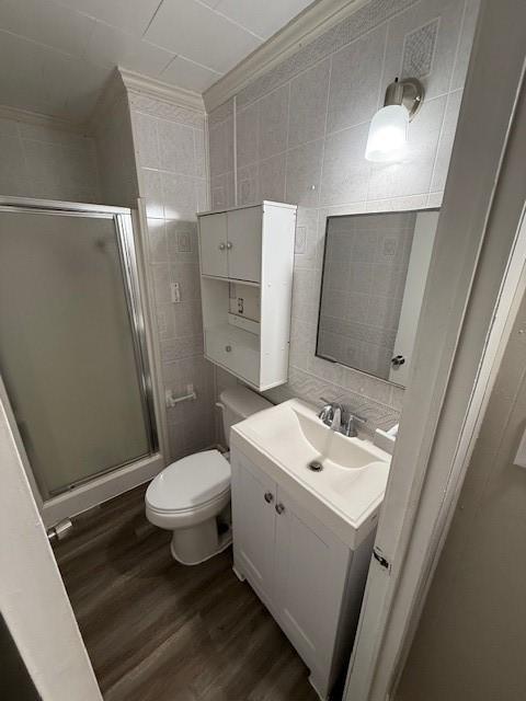 bathroom featuring walk in shower, vanity, wood-type flooring, and tile walls