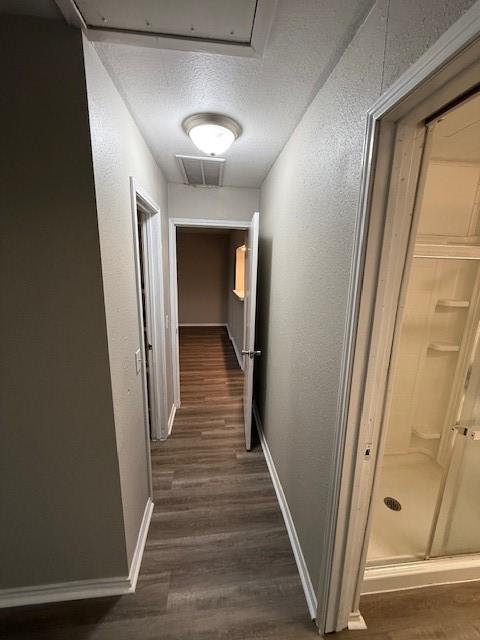 hallway with a textured ceiling and dark hardwood / wood-style flooring