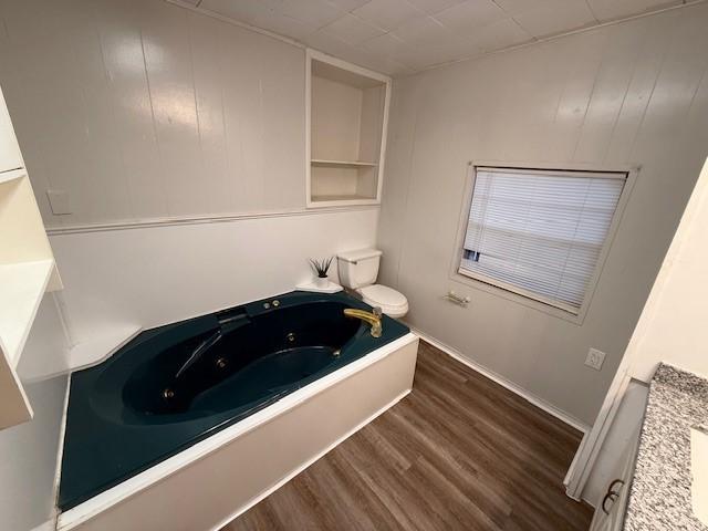 bathroom with vanity, a bath, and wood-type flooring