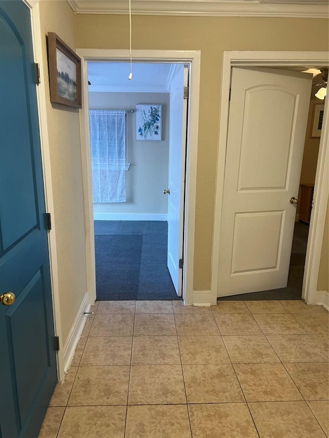 corridor with crown molding and light tile patterned floors