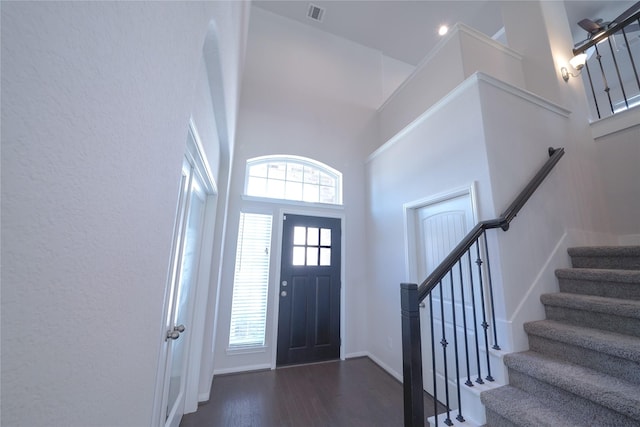 entryway featuring a healthy amount of sunlight, a towering ceiling, visible vents, and dark wood finished floors