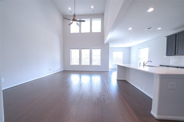 unfurnished living room with baseboards, visible vents, dark wood finished floors, and recessed lighting