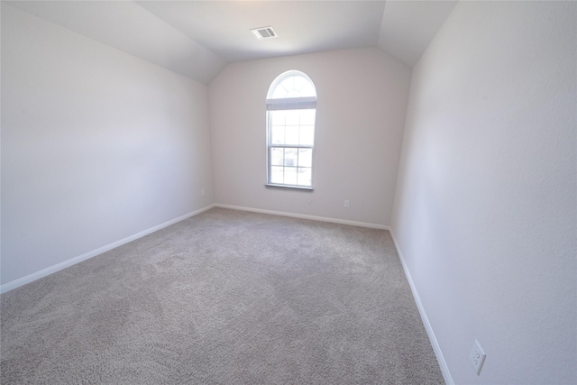 empty room featuring carpet floors, baseboards, visible vents, and lofted ceiling