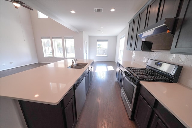 kitchen featuring under cabinet range hood, appliances with stainless steel finishes, open floor plan, and a sink