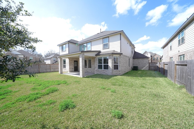 back of property featuring a yard, a patio, brick siding, and a fenced backyard