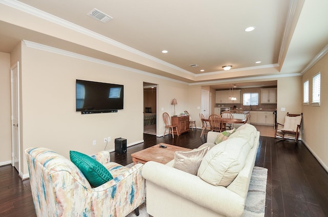 living room with ornamental molding, dark hardwood / wood-style flooring, and a tray ceiling