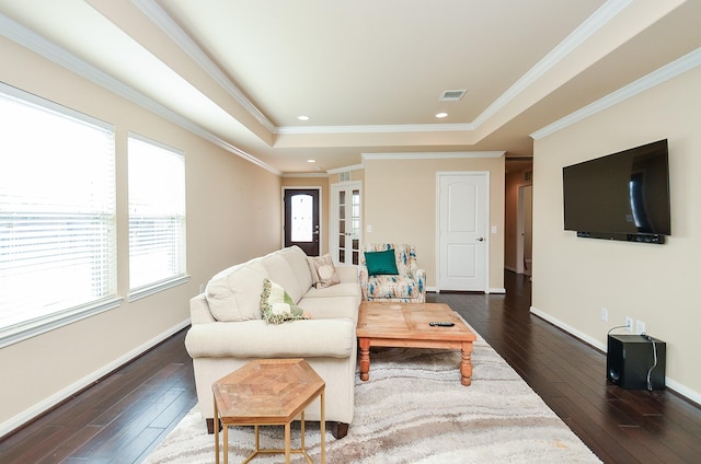 living room featuring ornamental molding, dark hardwood / wood-style flooring, and a tray ceiling