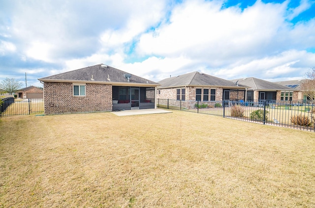 rear view of property featuring a sunroom, a patio, and a lawn