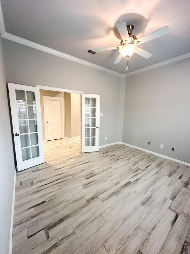 empty room with crown molding, light hardwood / wood-style floors, and french doors