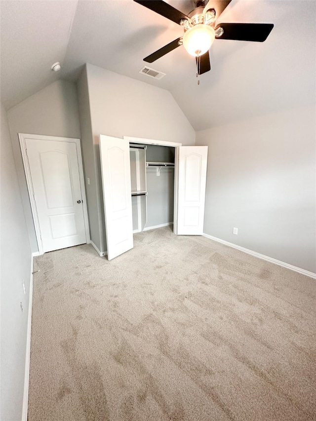 unfurnished bedroom with vaulted ceiling, light colored carpet, a closet, and ceiling fan