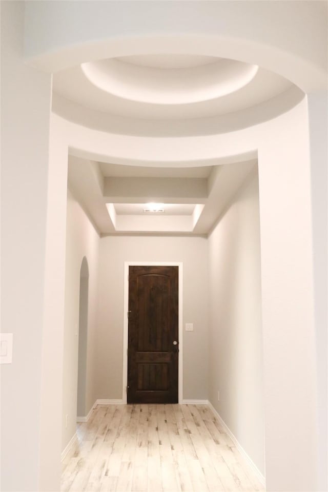 hallway featuring light hardwood / wood-style floors and a tray ceiling