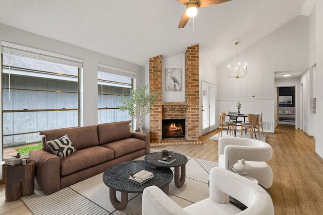 living room featuring vaulted ceiling, a textured ceiling, and light hardwood / wood-style flooring