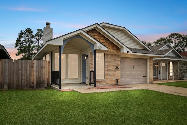 view of front of house with brick siding, a lawn, an attached garage, and fence