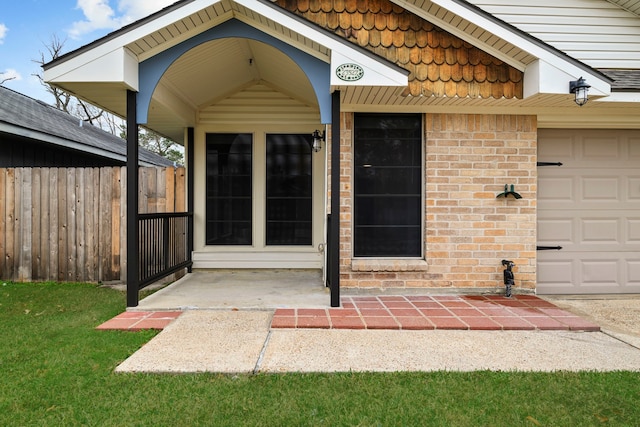 entrance to property with a garage, a yard, fence, and brick siding