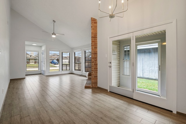 unfurnished living room with light wood finished floors, high vaulted ceiling, and ceiling fan with notable chandelier