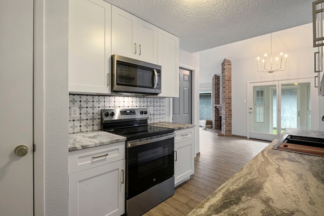 kitchen with decorative backsplash, light wood-style flooring, appliances with stainless steel finishes, light stone counters, and white cabinetry