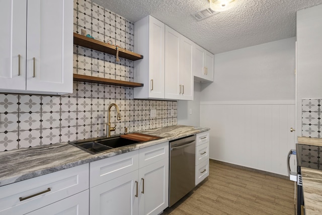 kitchen featuring a sink, white cabinets, stainless steel dishwasher, wainscoting, and open shelves