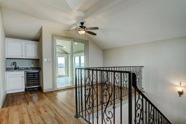 corridor featuring sink, lofted ceiling, beverage cooler, and light hardwood / wood-style floors