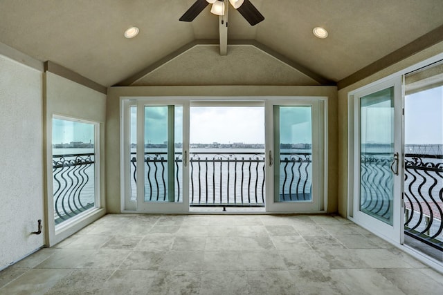 unfurnished sunroom with lofted ceiling, ceiling fan, and a water view