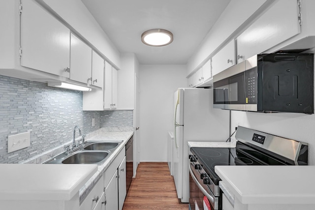 kitchen with backsplash, appliances with stainless steel finishes, white cabinetry, a sink, and wood finished floors